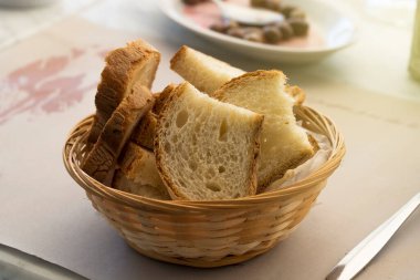 Restoran masasında dilimlenmiş bir sepet İtalyan ekmeği.