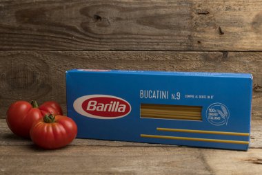 Carrara, İtalya - 17 Temmuz 2021 - Tahta bir masada iki domatesli bir paket Barilla bucatini