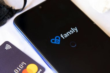 Carrara, İtalya - 27 Ağustos 2021 - Siyah dantelli sutyen ve kredi kartlı cep telefonu Fansly logosunu gösteriyor.