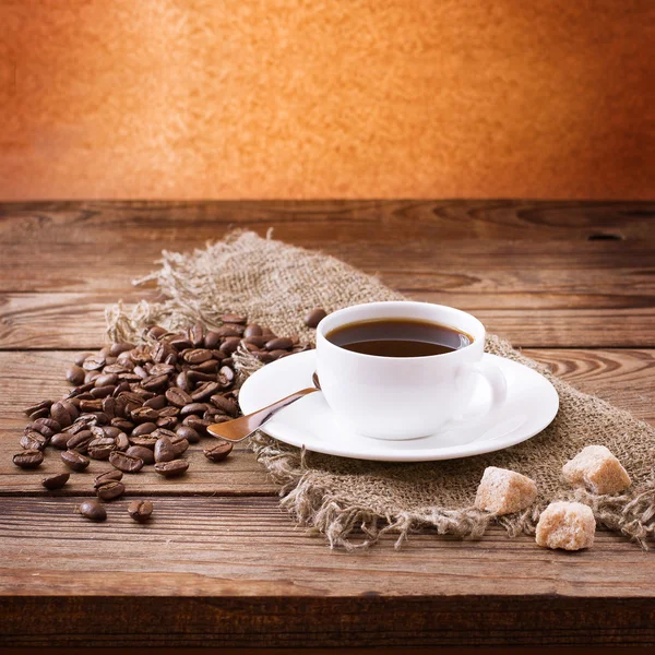 Tasse Kaffee, Süßigkeiten und geröstete Bohnen. — Stockfoto