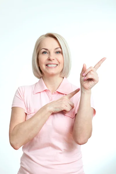 Friendly smiling middle aged woman pointing at copyspace isolated Stock Image