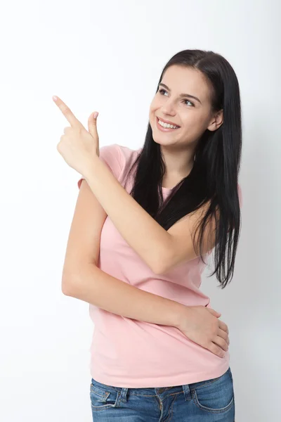 Vriendelijk lachende vrouw wijzend op copyspace geïsoleerd op witte achtergrond — Stockfoto