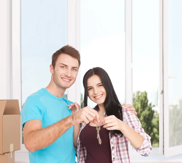 Las llaves de su nueva casa. Joven pareja alegre sosteniendo la llave . — Foto de Stock