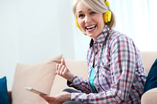 Mooie vrouw in lichte outfit genieten van muziek thuis — Stockfoto