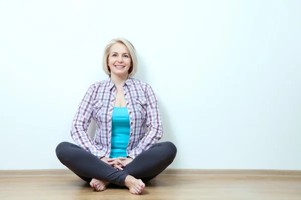 스튜디오에서 흰색 바탕에 패션 의류에 교차 다리와 바닥에 앉아 행복 한 여자 — 스톡 사진