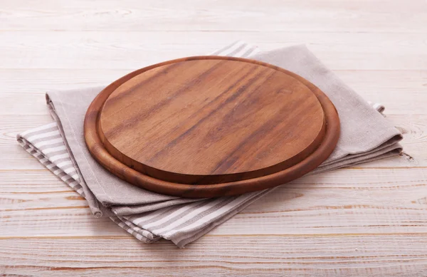 Pizza board with napkin on wooden table. Top view mockup