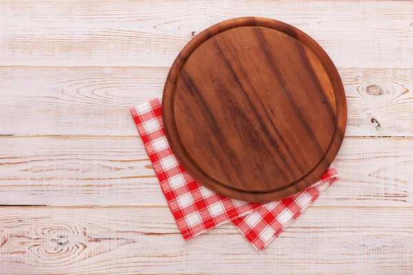 Pizza board with napkin on wooden table. Top view mockup