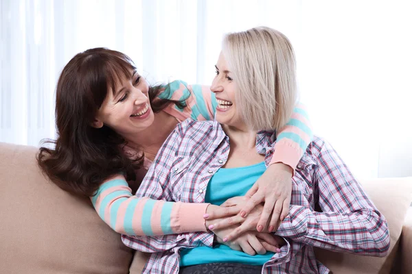 Twee gelukkige vrouwelijke vrienden genieten van een gesprek in de woonkamer thuis — Stockfoto