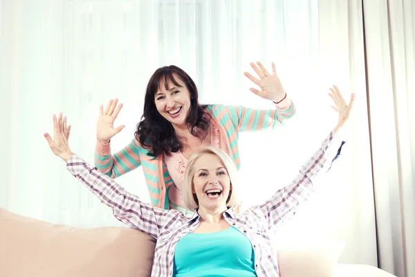 Deux amies heureuses profitant d'une conversation dans le salon à la maison — Photo