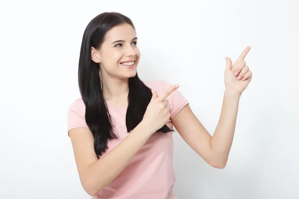 Vriendelijk lachende vrouw wijzend op copyspace geïsoleerd op witte achtergrond — Stockfoto