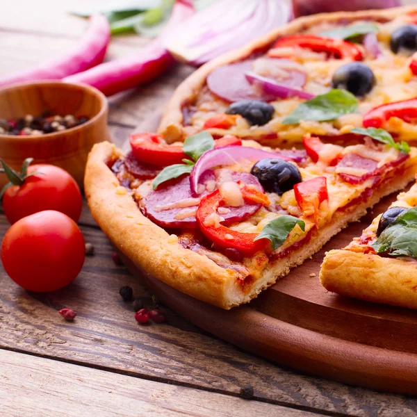 Pizza con jamón, pimienta y aceitunas. Deliciosa pizza fresca servida en mesa de madera . —  Fotos de Stock