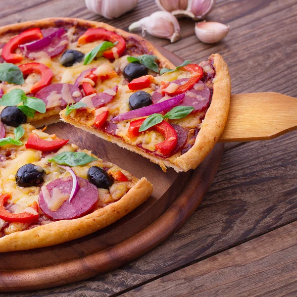 ハム、コショウとオリーブのピッツァ木製のテーブルで提供していますおいしい新鮮なピザ. — ストック写真