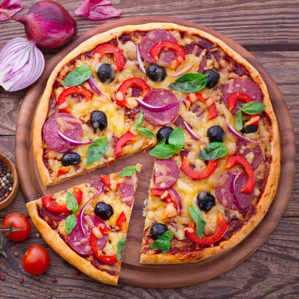 Pizza con jamón, pimienta y aceitunas. Deliciosa pizza fresca servida en mesa de madera . — Foto de Stock