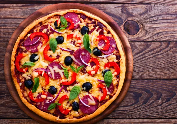 Pizza mit Schinken, Pfeffer und Oliven. leckere frische Pizza auf Holztisch serviert. — Stockfoto