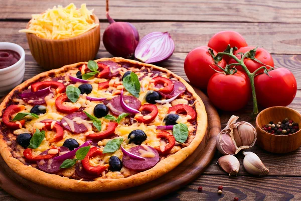 Пицца с ветчиной, перцем и оливками. Вкусная свежая пицца на деревянном столе . — стоковое фото