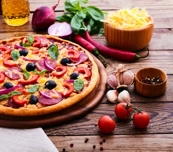 Pizza with ham, pepper and olives. Delicious fresh pizza served on wooden table. — Stock Photo, Image