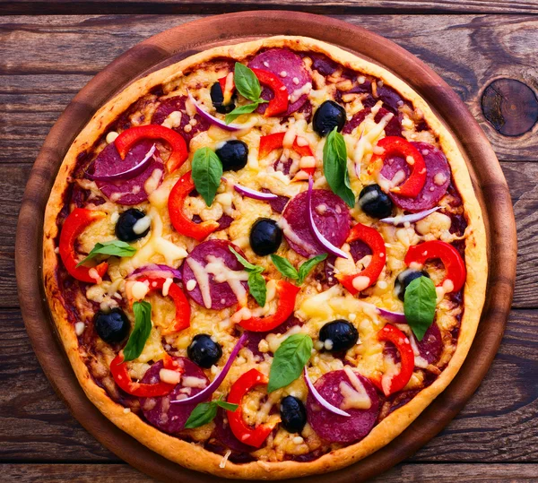 Pizza med skinka, paprika och Oliver. läckra färsk pizza serveras på träbord. — Stockfoto