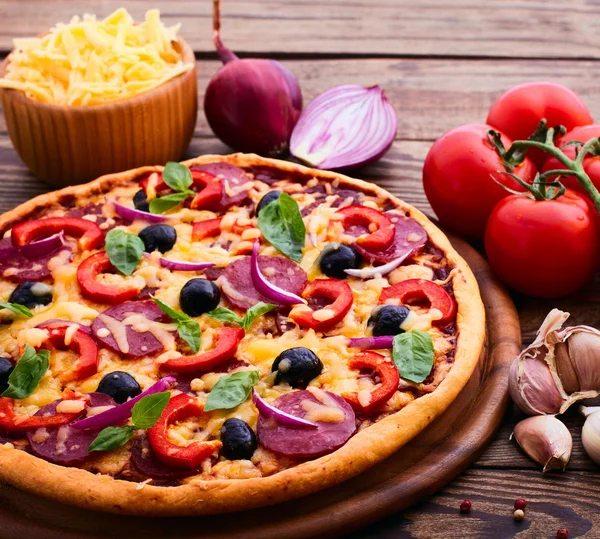 与火腿、 辣椒和橄榄的披萨。美味的新鲜披萨送达木制的桌子上. — 图库照片