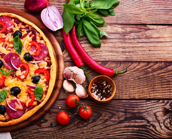 Pizza com presunto, pimenta e azeitonas. Deliciosa pizza fresca servida em mesa de madeira . — Fotografia de Stock