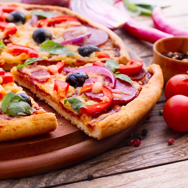 Pizza med skinka, paprika och Oliver. läckra färsk pizza serveras på träbord. — Stockfoto