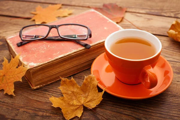 Feuilles d'automne, livre et tasse de thé sur table en bois en studio — Photo