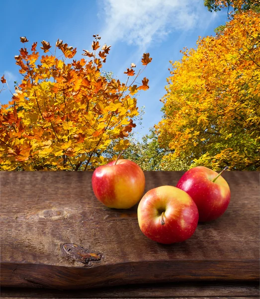 Apples on wooden table over autumn landsape — Stock Photo, Image