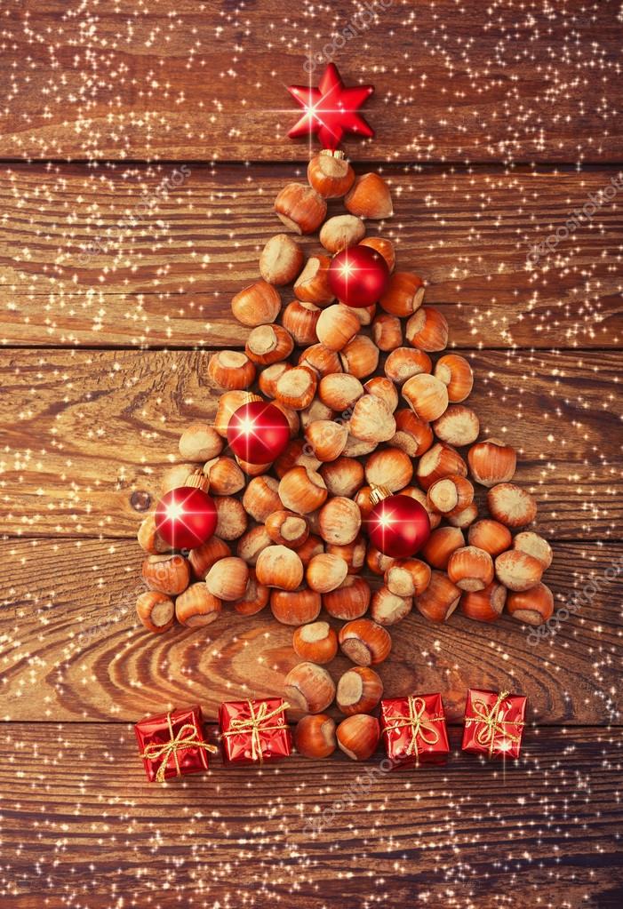 Christmas tree made of hazelnuts with red baubles and gifts — Stock