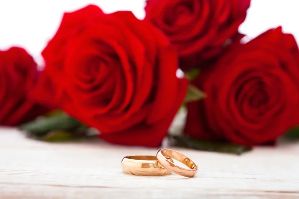 Svatební prsteny a svatební kytice rudých růží. — Stock fotografie