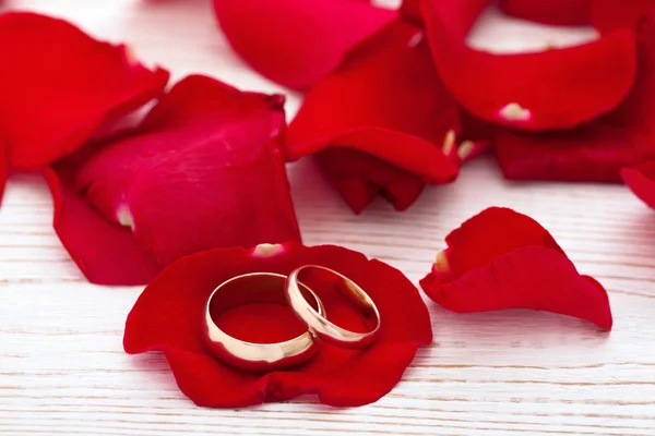 Svatební prsteny a svatební kytice rudých růží lístků. — Stock fotografie