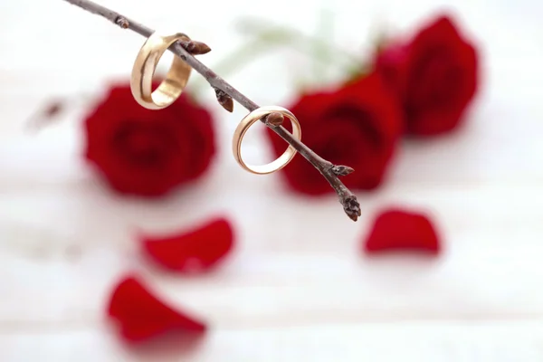 Wedding rings and wedding bouquet of red roses petals. — Stock Photo, Image