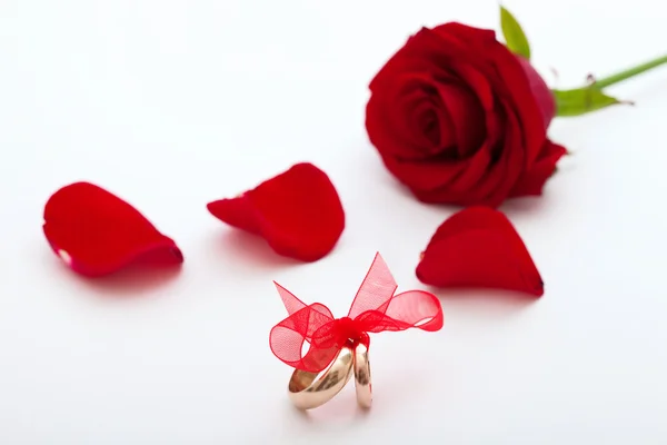 Esküvői gyűrűk és esküvői csokor, szirmok piros rózsa. — Stock Fotó