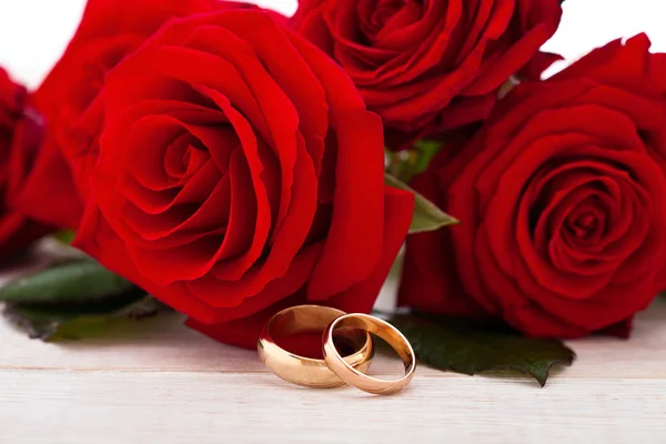 Wedding rings and wedding bouquet of red roses. — Stock Photo, Image
