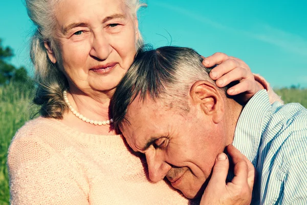 Äldre par omfamnar varandra på landsbygden — Stockfoto