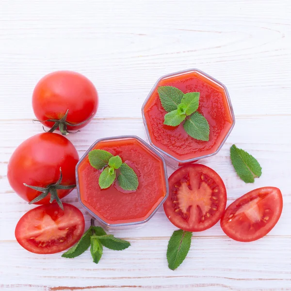 Jus de tomate aux légumes sur table en bois blanc . — Photo