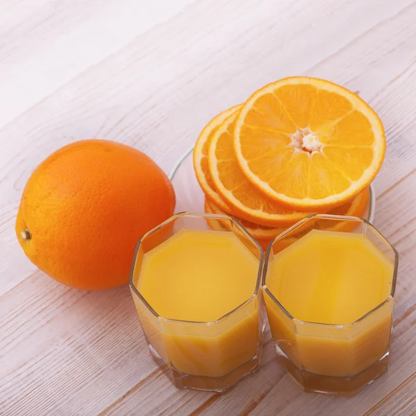 Orangensaft mit geschnittener Orangenhälfte auf Holztisch — Stockfoto