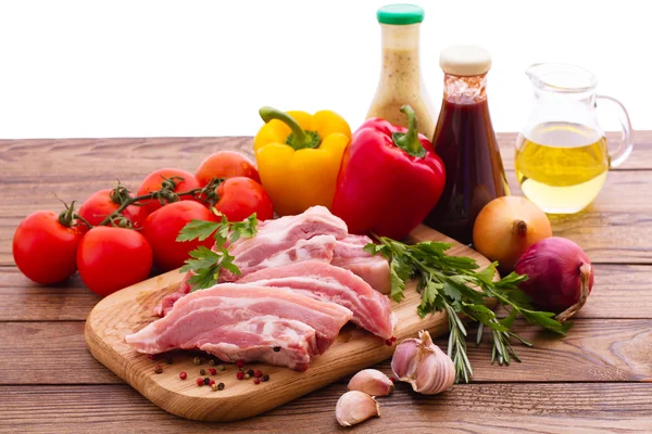 Їжа. Сире м'ясо для барбекю з овочами на дерев'яній поверхні . — стокове фото