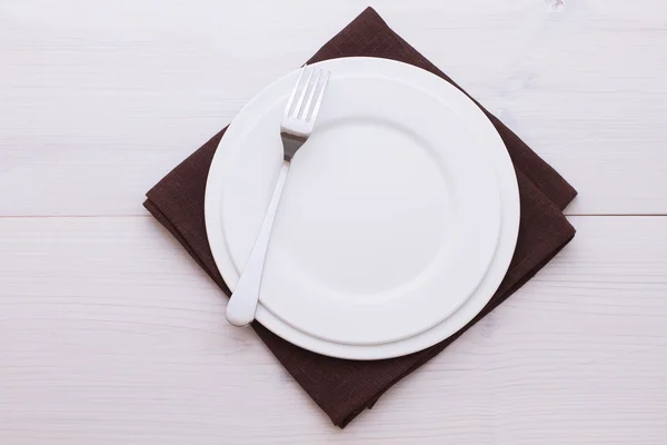 Prázdné talíře, příbory, ubrusy na bílý stůl k večeři. — Stock fotografie