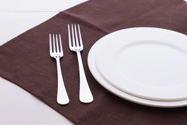 Lege platen, bestek, tafelkleed op witte tafel voor het diner. — Stockfoto