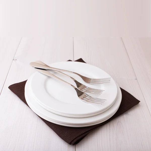 Empty plates, cutlery, tablecloth on white table for dinner. — Stock Photo, Image