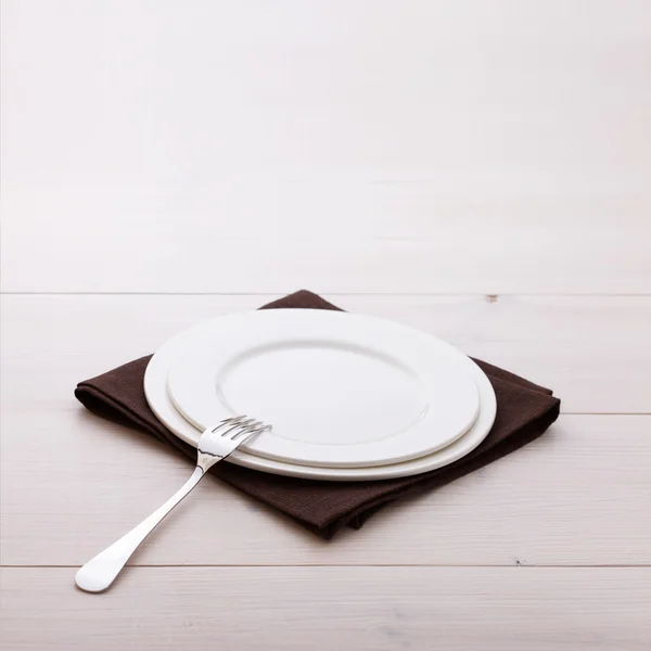 Empty plates, cutlery, tablecloth on white table for dinner. — Stock Photo, Image