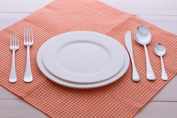 Άδειο πιάτα, μαχαιροπήρουνα, τραπεζομάντιλο στο λευκό τραπέζι για δείπνο. — Φωτογραφία Αρχείου
