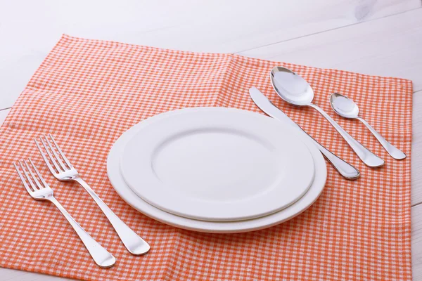 Empty plates, cutlery, tablecloth on white table for dinner. — Stock Photo, Image