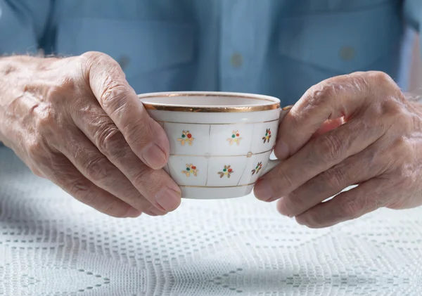 Senior homme tenant une tasse de thé dans leurs mains à table close-up — Photo