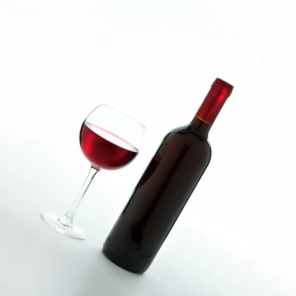 Glass and bottle of red wine unusually on white background. — Stock Photo, Image