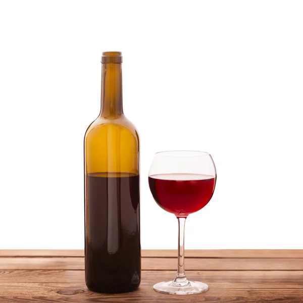 Glass and bottle of red wine unusually on wooden background. — Stock Photo, Image