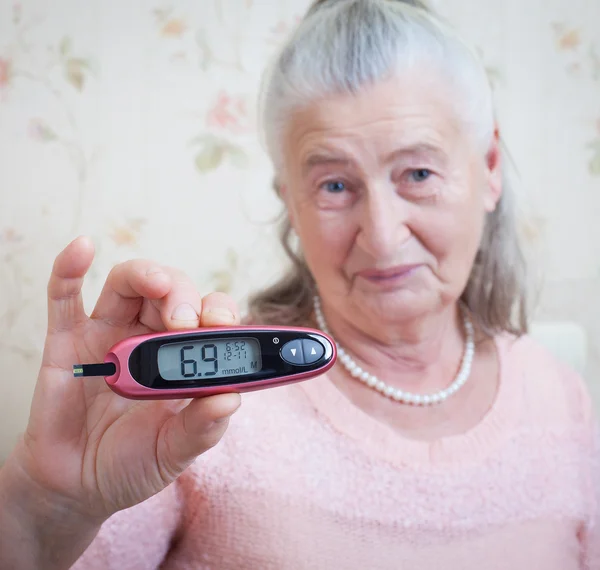 Medicina, edad, diabetes, cuidado de la salud y concepto de personas - mujer mayor con glucómetro que comprueba el nivel de azúcar en sangre en el hogar — Foto de Stock