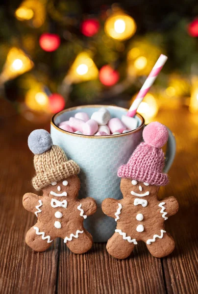 一杯热巧克力和棉花糖放在木制桌子上 上面有姜饼人和圣诞装饰 图库照片