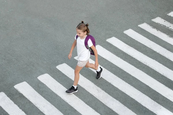 Liseli kız okula giderken karşıdan karşıya geçiyor. Zebra trafiği şehrin öbür ucunda. Yaya geçidinden geçen yayalar. Sırt çantasıyla gezen şık bir genç kız. Aktif çocuk. Üst görünüm