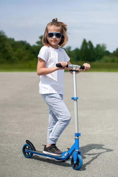 Çocuk sürme scooter. Renkli tekme tahtada evlat. Etkin açık eğlenceli çocuklar için. Okul öncesi çocuklar için yaz spor. Mutlu kız Bahar park. Sağlıklı bir yaşam tarzı kavramı