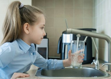 Çocuğun elinde şeffaf bir cam var. Bardak içeceği dolduruyorum. Taze içki dolduruyorum. Musluk suyu tüketimi plastik şişelerde suyun korunmasına ve çevrenin korunmasına katkıda bulunur.